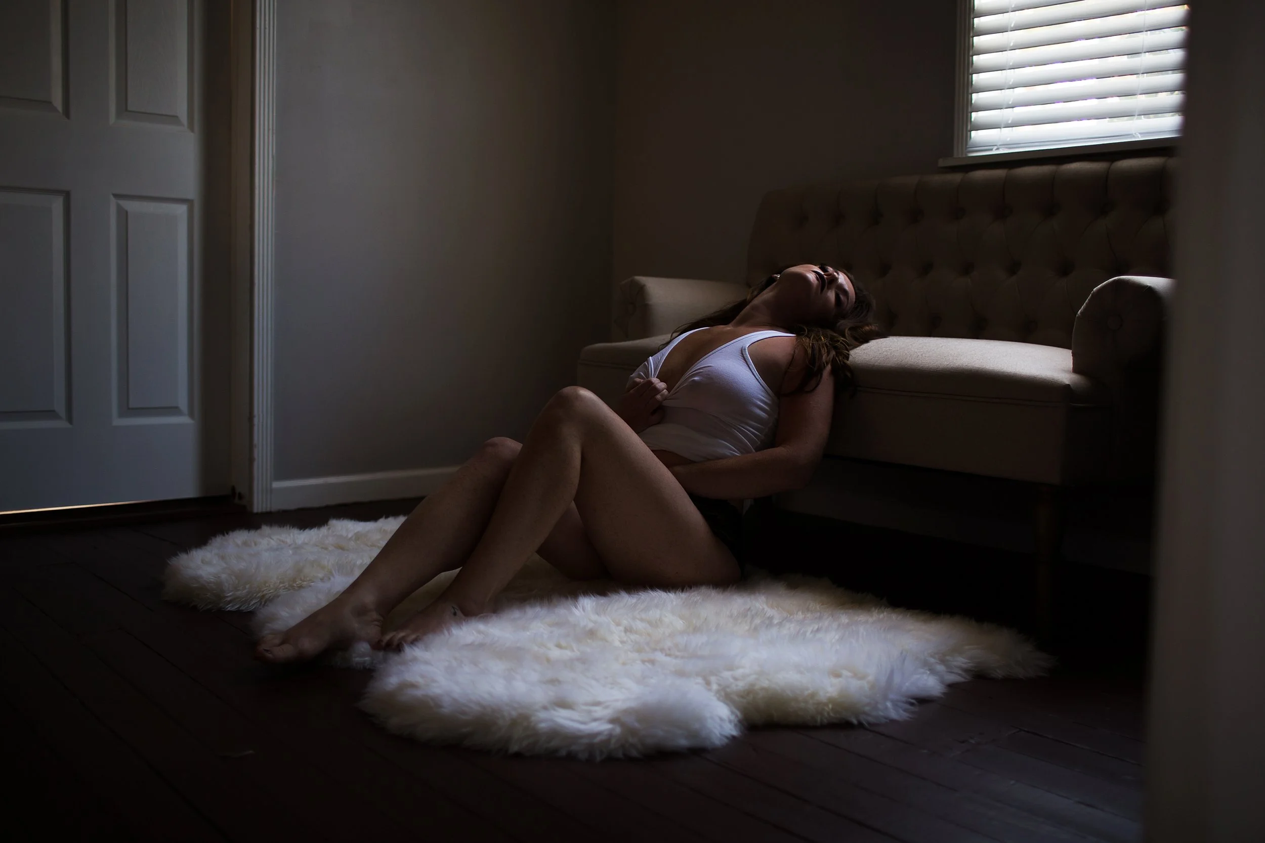 Woman leaning onto couch with wet tshirt on sheep skin throw rug