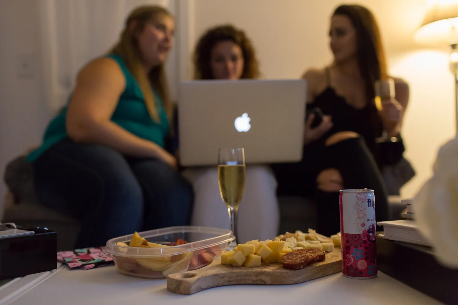 Drinks and snacks laid out on a table in front of women looking at a computer