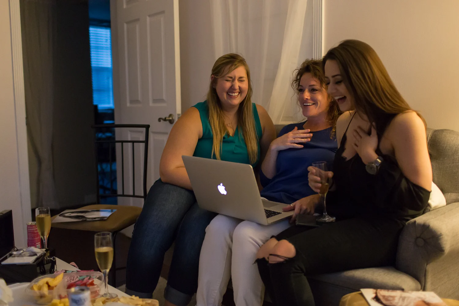 Three girls laughing together on couch