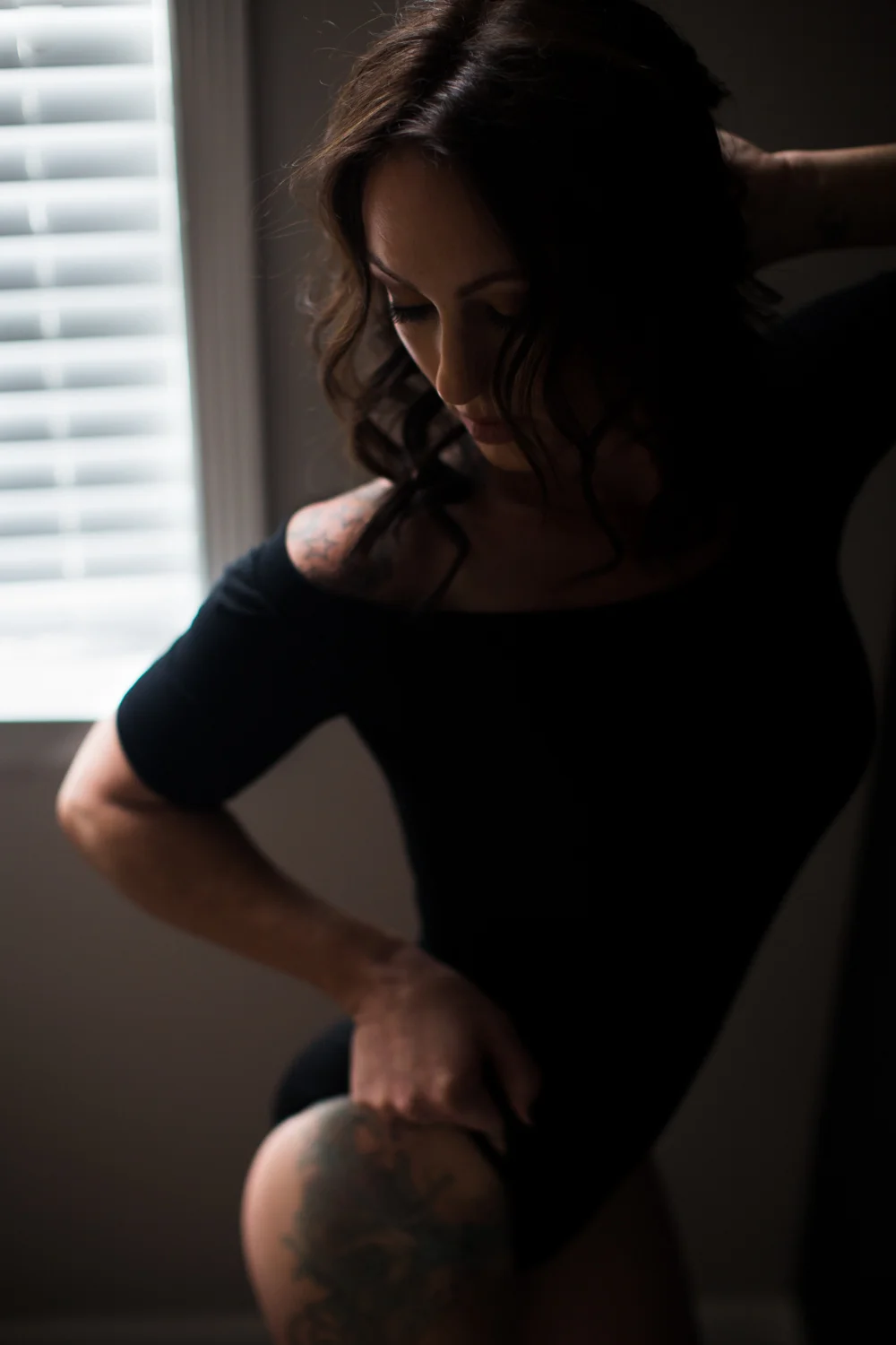 Woman in black bodysuit with hip and shoulder tattoo
