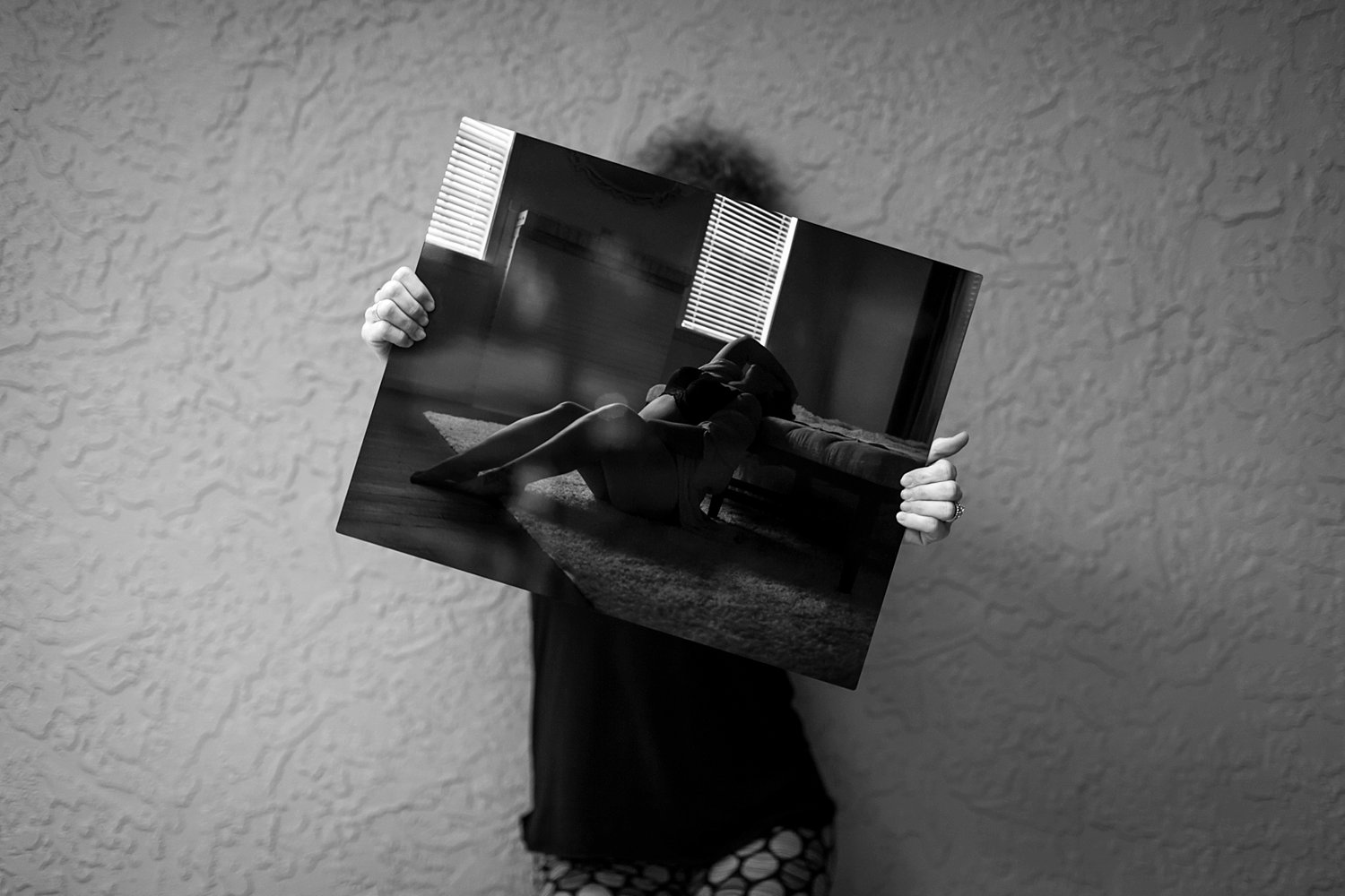 Woman holding a large photo, leaning against a wall