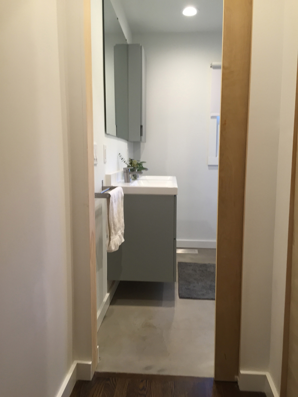 Floating vanity. Concrete floor. That is a pocket door on the right. Very simple and clean.