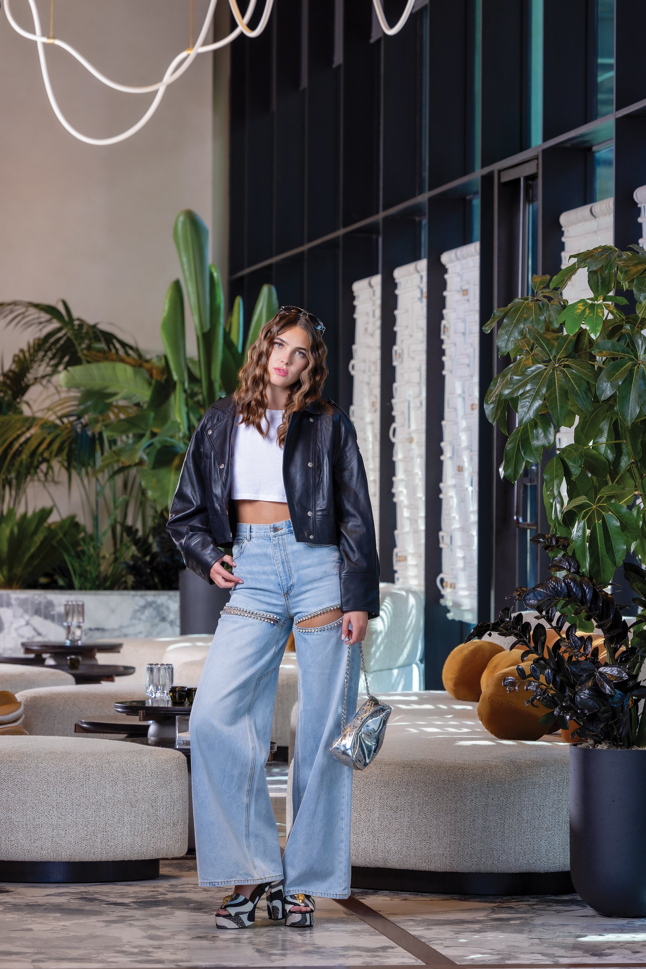   SUNGLASSES:  Silver and blue, Oliver Peoples, $79.95.  JACKET:  Black leather bomber, Envelope, $275.  TOP:  White cropped short-sleeved T-shirt, Alexander Wang, $89.95.  PANTS:  Blue jeans with embellished cutouts, $245.  HANDBAG:  Silver patterne