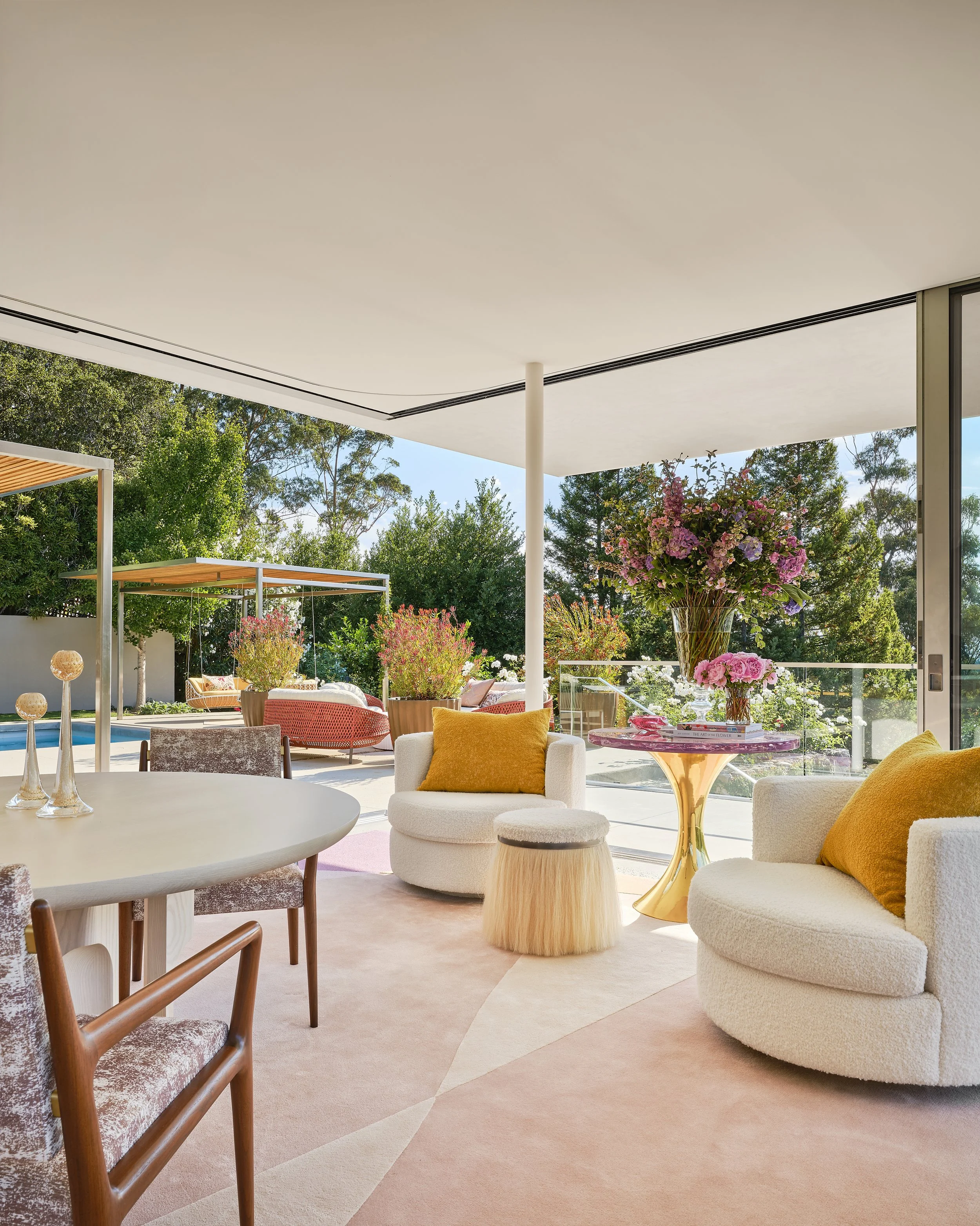 Living room with large glass sliding doors opening to a patio with outdoor furniture, including a potted plant, chairs, and greenery in the background.