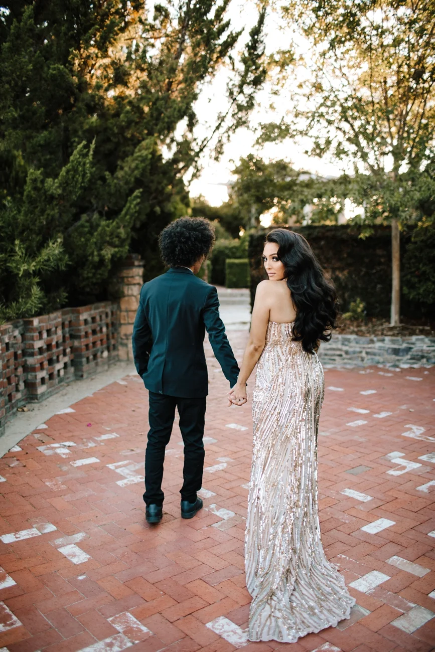 Engagement session with glamorous dress looking over shoulder at estate in Los Angeles