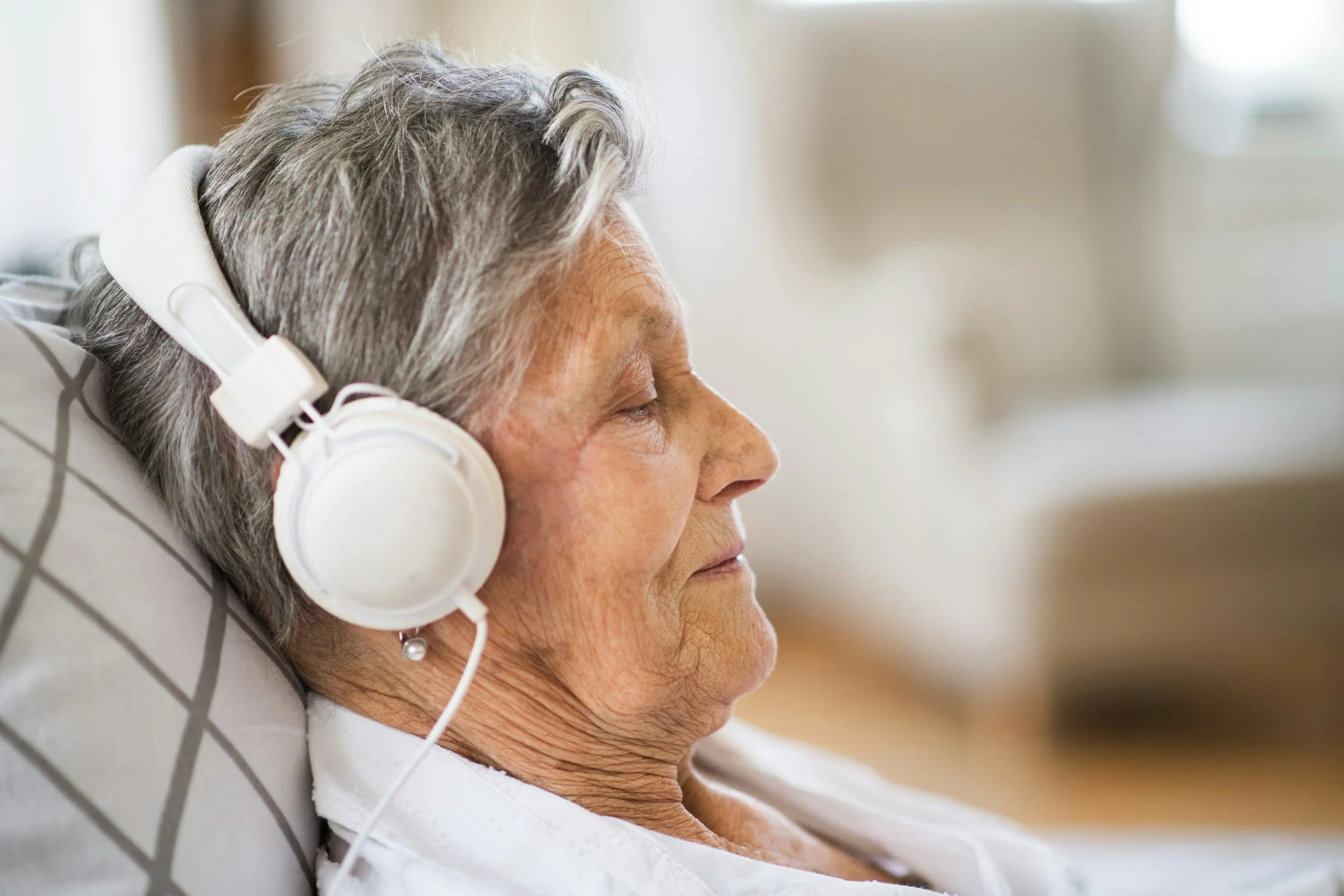 an older woman listens to music on headphones
