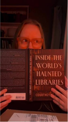 author courtney m block holding one of her books in front of her face