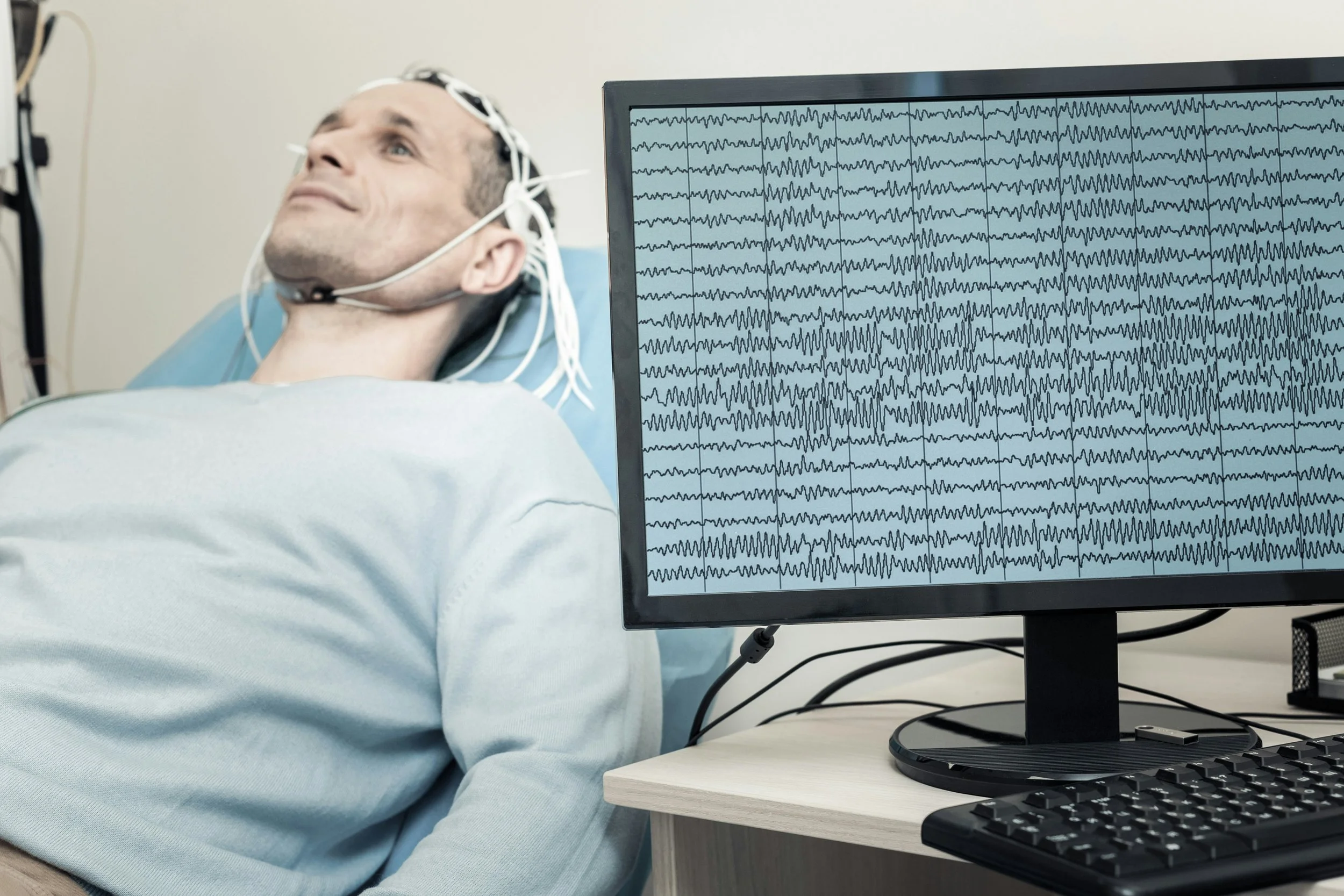 a man wearing a neurofeedback cap attached to a computer