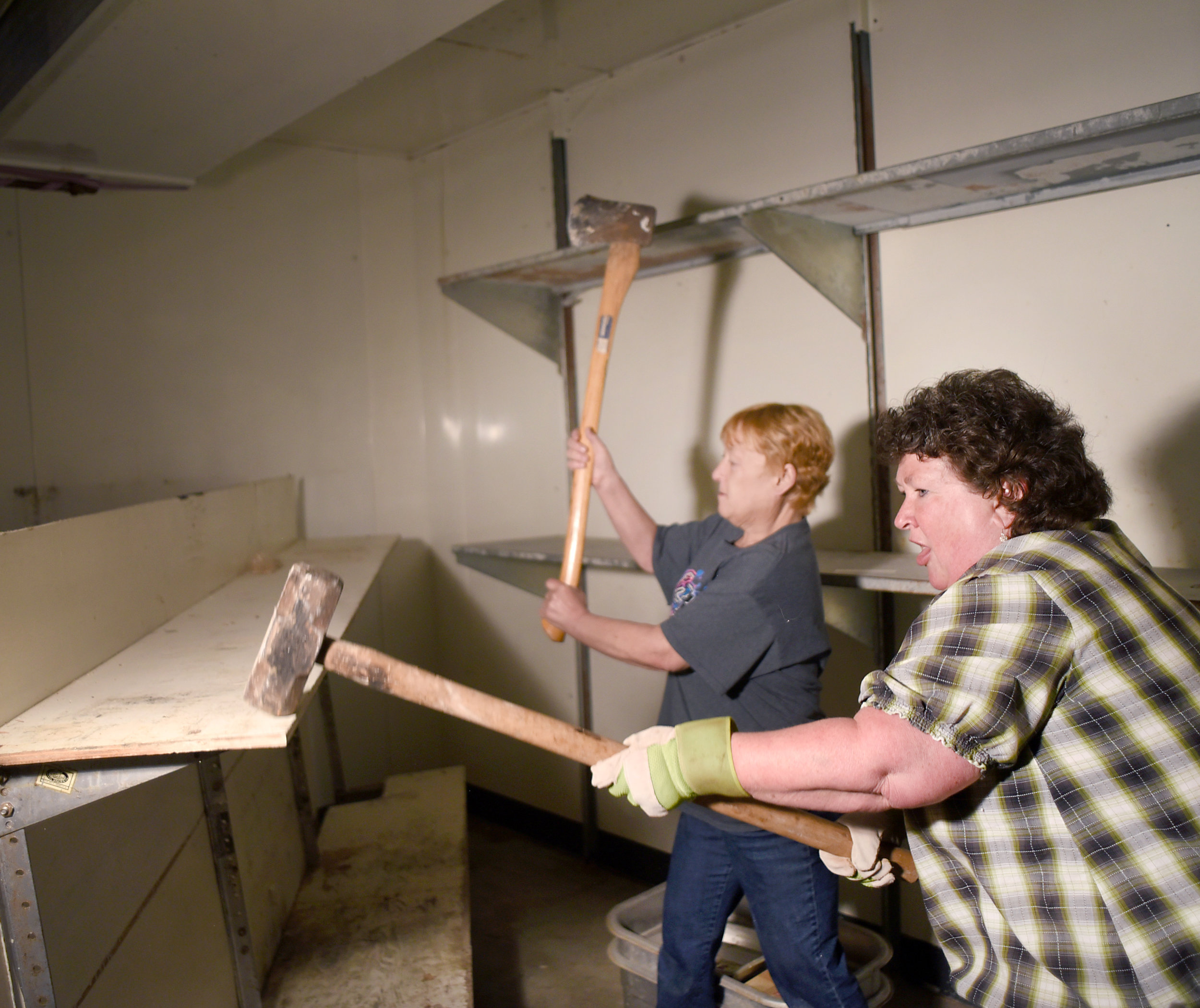  Laurie Hanson, of Argyle, and Muffy Rhyner, of Lake Geneva, try to break apart an old shelf during the renovation of Belle's Argyle Grocery on April 21, 2016. &nbsp; 