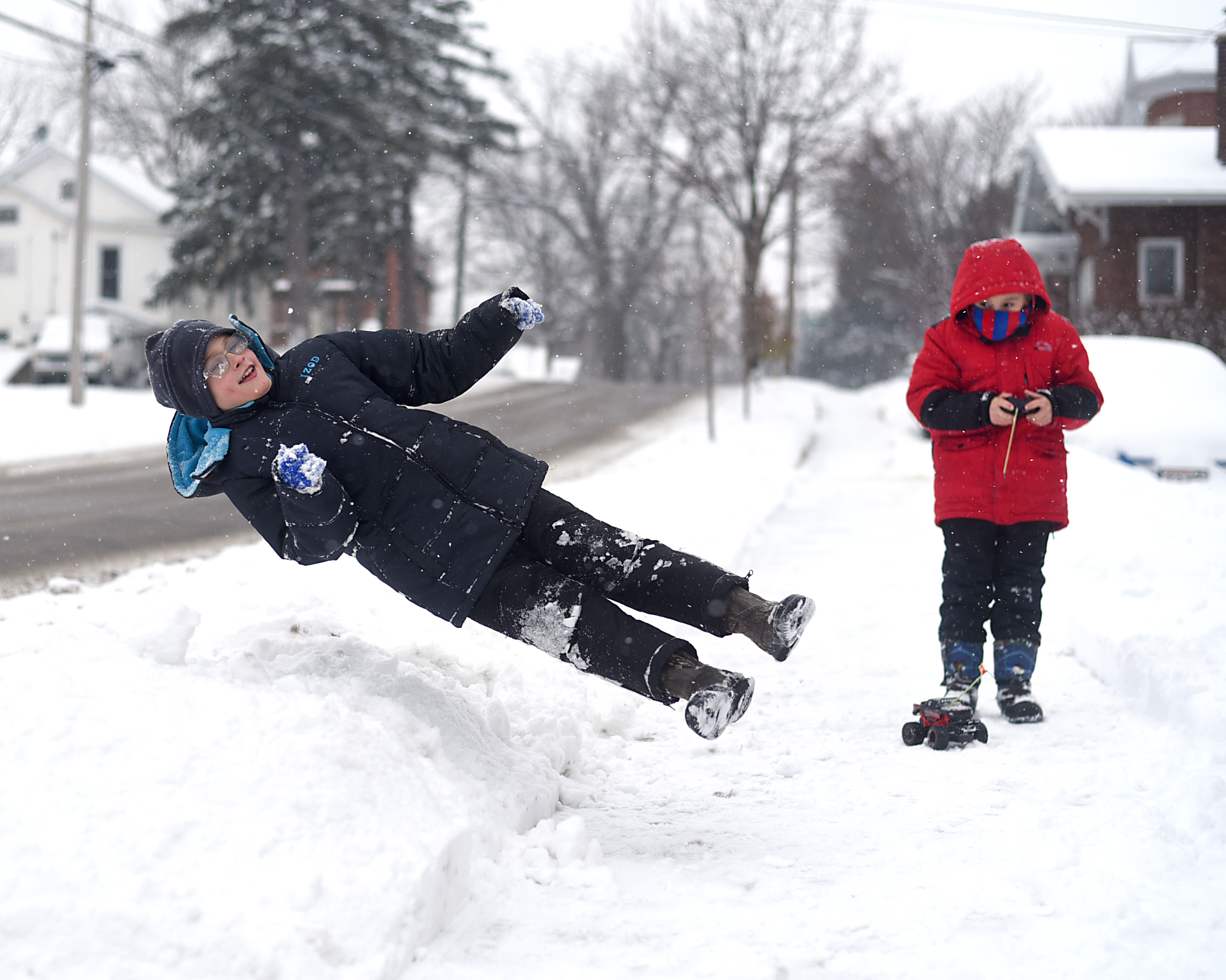  Malaki Cooter, 9, jumps into a pile of snow while his brother, Kayden Cooter, 6, tries to drive a remote controlled car on the sidewalk outside their home in Monroe Dec. 11, 2016. The brothers were enjoying the snow and made several snow angels. 