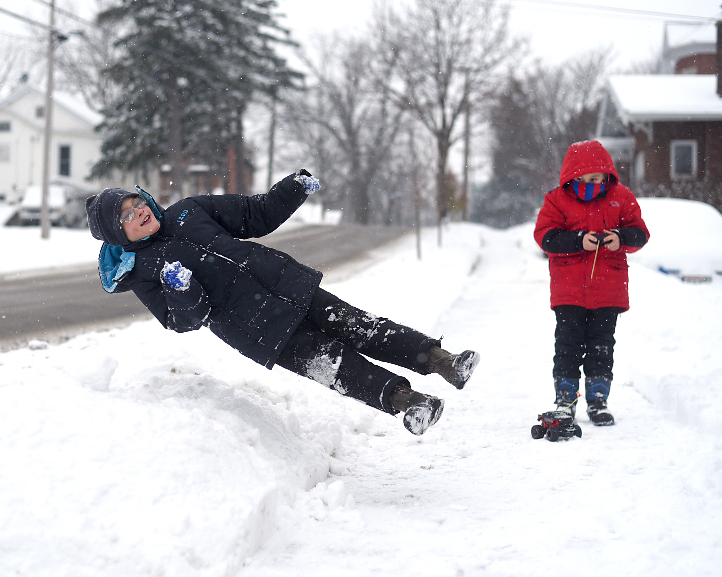 Malaki Cooter, 9, jumps into a pile of snow while his brother, Kayden Cooter, 6, tries to drive a remote controlled car on the sidewalk outside their home in Monroe Dec. 11, 2016. The brothers were enjoying the snow and made several snow angels.