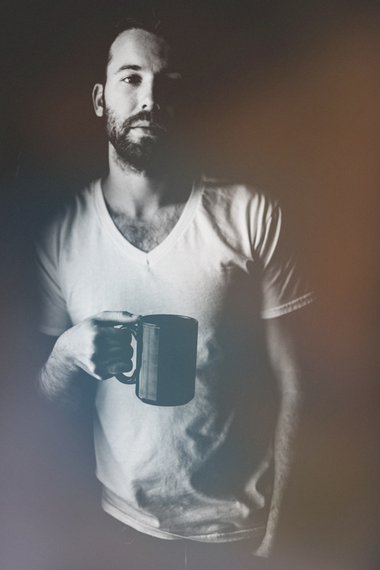 Daniel Alkato holding a coffee mug black and white