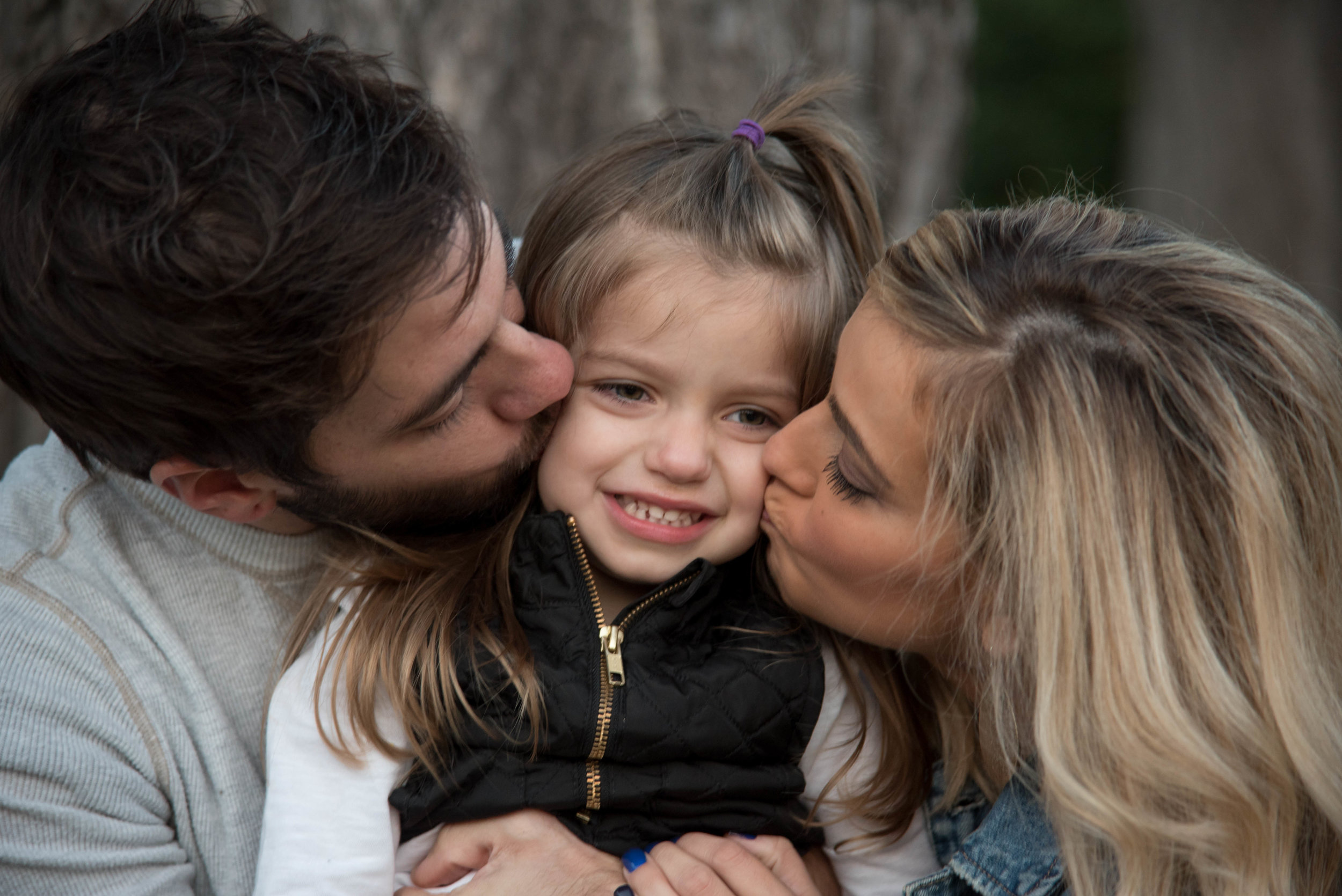 Girl being kissed by mom and dad in St Louis