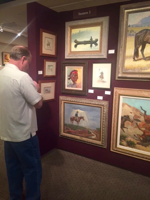 A collector studies a Joe Beeler (1931-2006) oil on canvas estimated at $4,000-$6,000