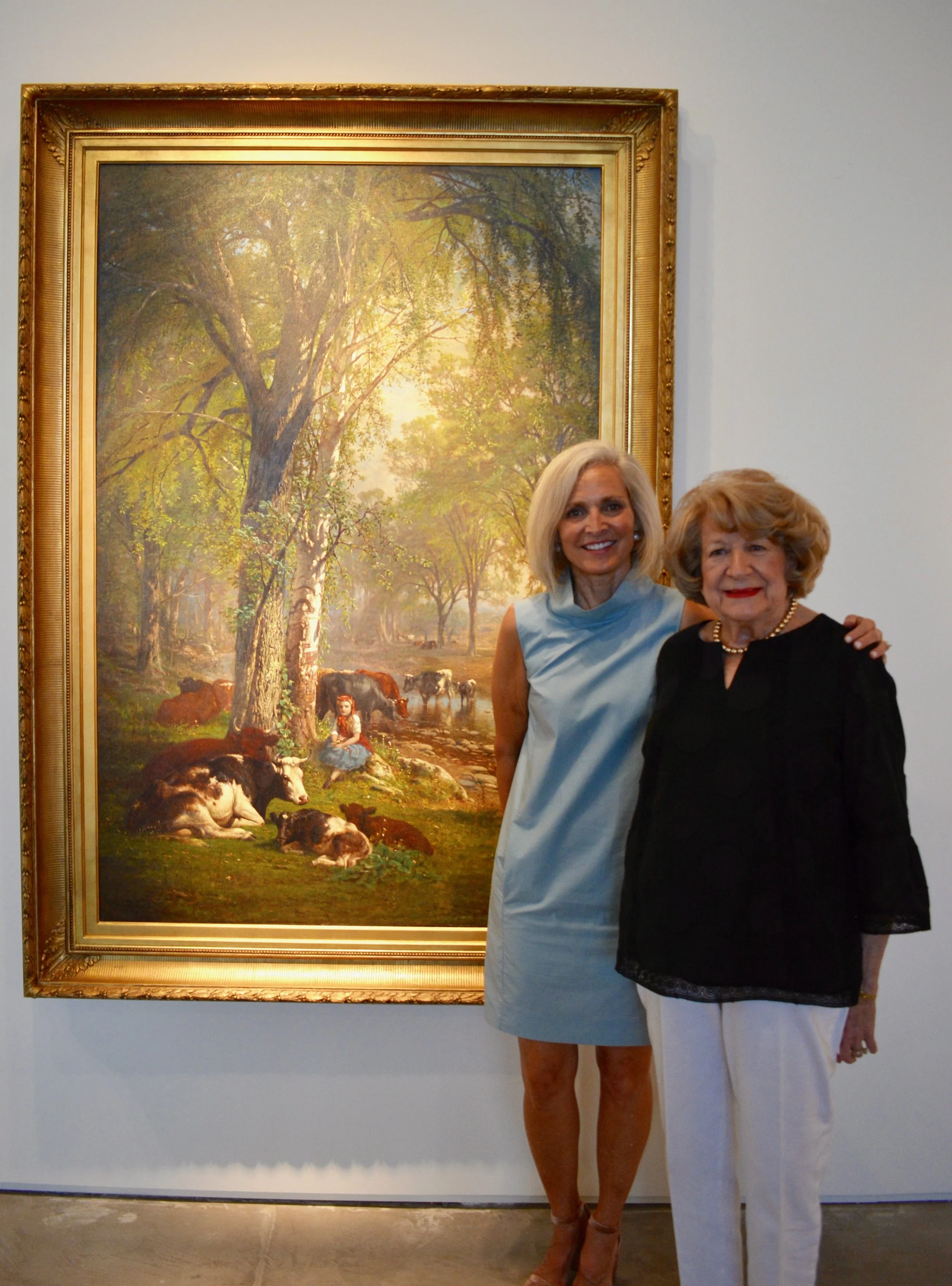 Kathryn Schorr standing with Judy Jackson in front of “Among Friends” by James McDougal Hart