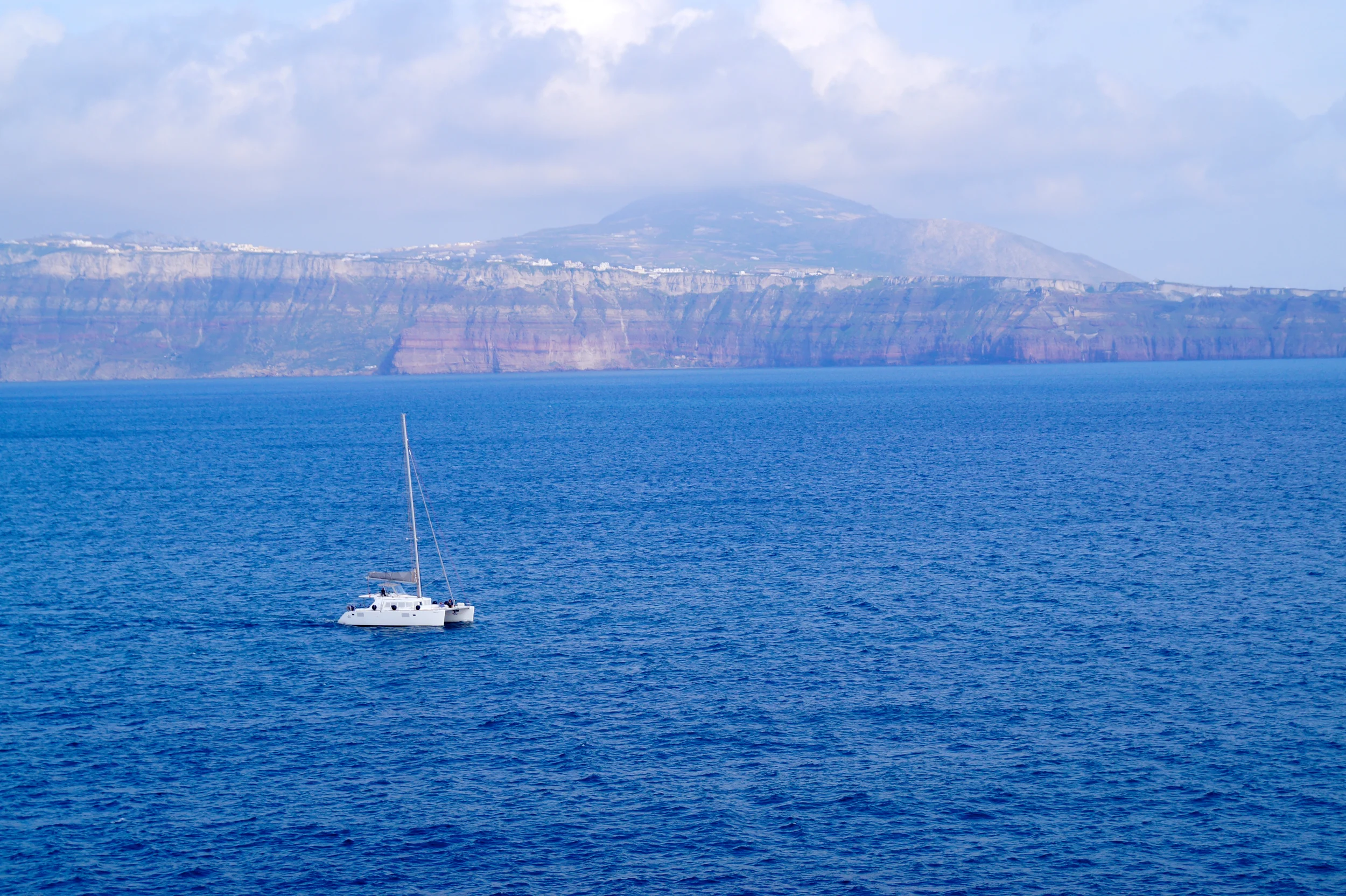 Sailboat in Santorini with the cliffs in the distance.