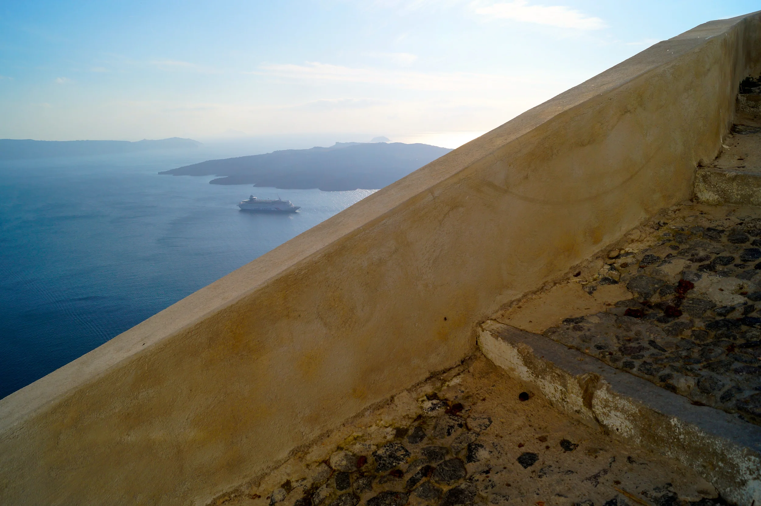 The stairs on the cliffs looking out over the Sea with the volcano and cruise ship next to it.