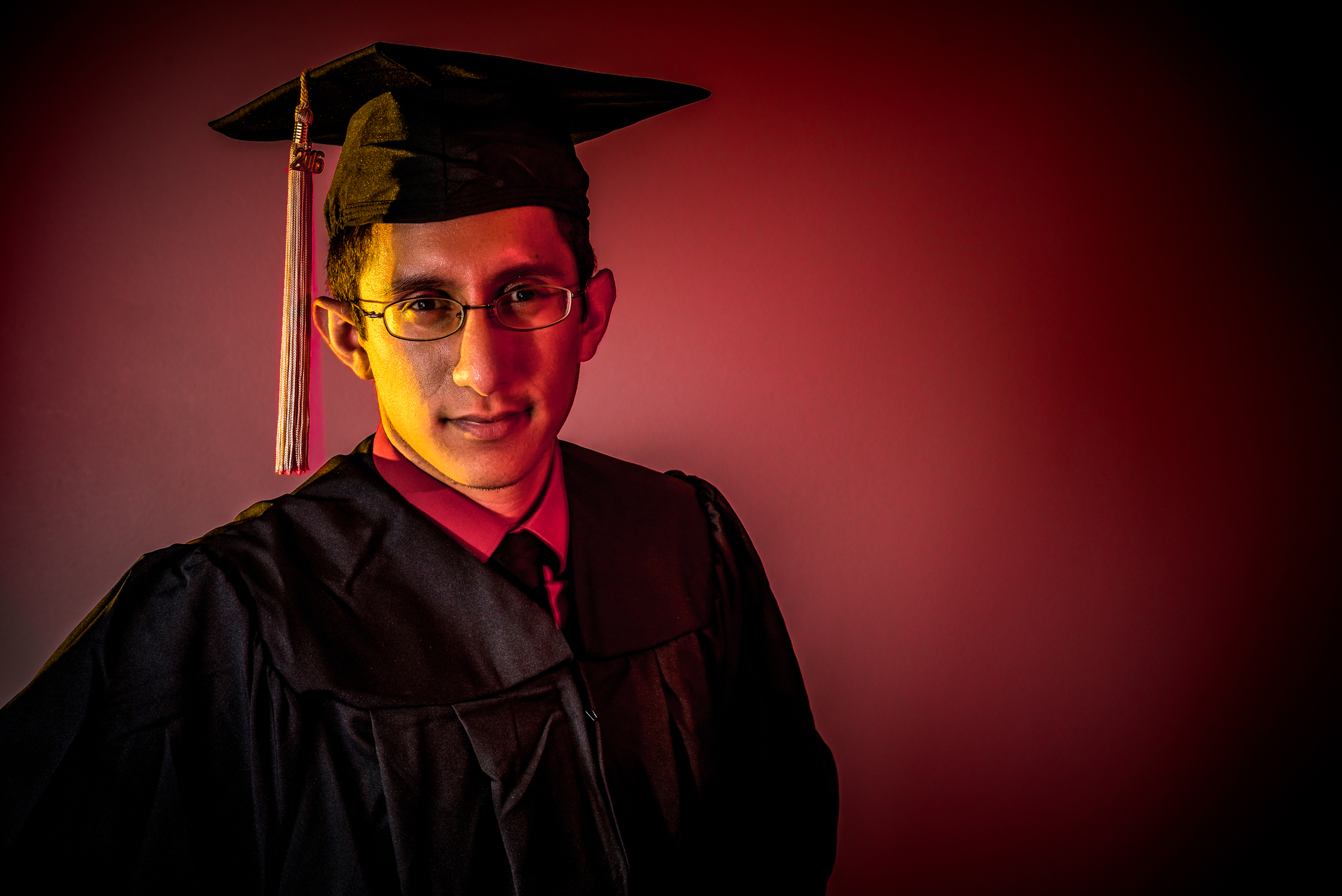 Alberto with red and gold light on his face and a red background.
