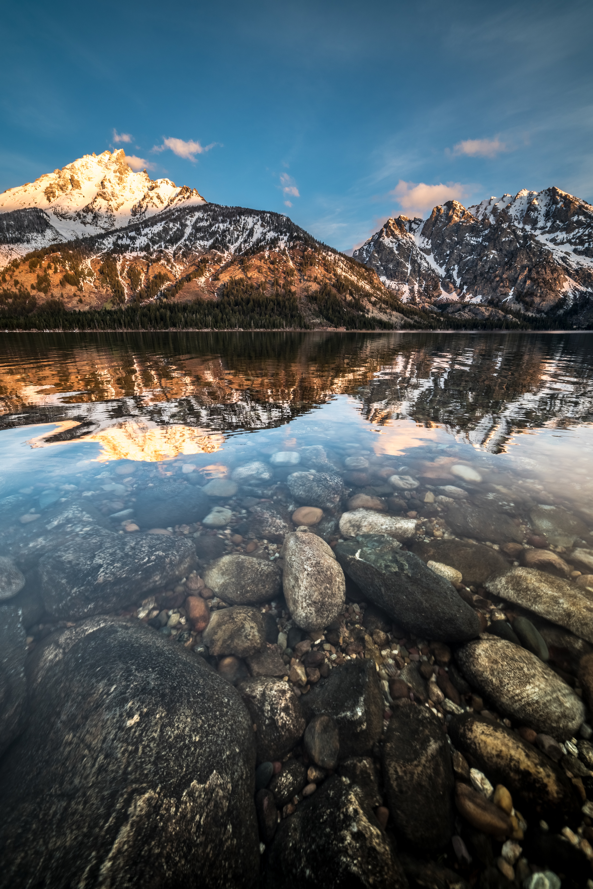 A vertical composition showing off how clear the water is in Jenny Lake as the morning sun kisses the peak of Grand Teton.