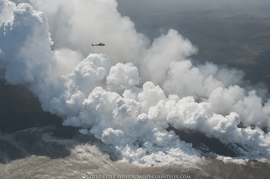 A helicopter hovers above the lava ocean entry.