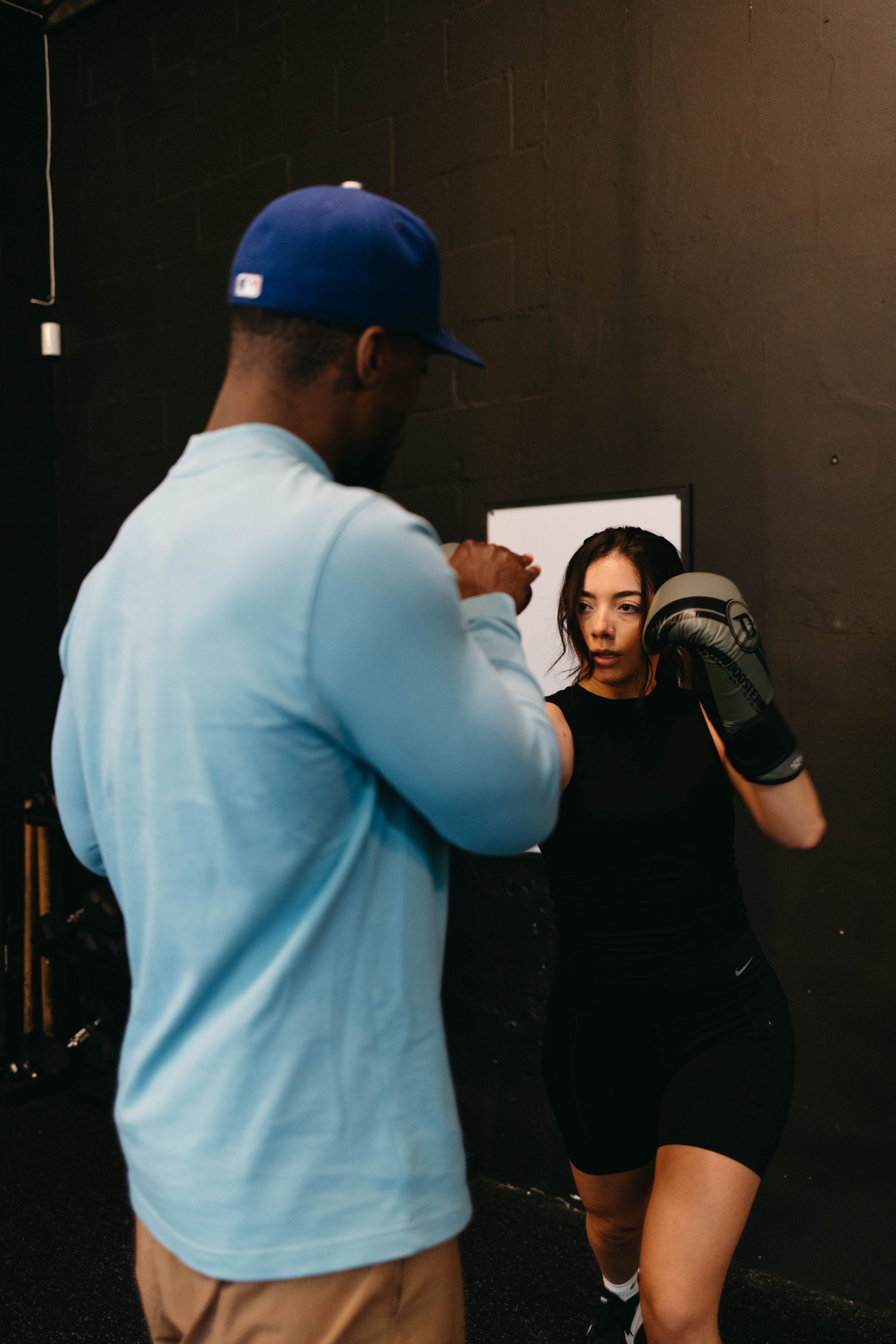 Woman in gym gear boxing with a man in a blue shirt.