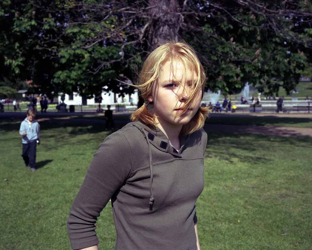 Blaue Blume 'She was fifteen. She didn't like this picture, her mom loved it and put it on the wall in their home for a long time.' I am interested in observing emotions we have in our lives, how they might transform us. For my project, 'Blaue Blume', I have taken pictures of 15 year old girls in London. I met them on the street and asked them to show me their serious selves. While I was taking picture, I didn't talk to them. The silence between us produced tension and the girl's faces changed in a few minutes. I wanted to capture both the nervousness and the loneliness of the girl through her facial and body expression while in front of my lens. I wished to create an uncomfortable situation with them. 15 is very much a transitional age, a time when girls are very aware they are becoming women. Their bodies and minds are changing and they are often confused about their identity, about who they might become. Their surroundings start to treat them as little women. They are frustrated but there appears to be no reason for it, they lack self control and are based on conflicts between physical and psychological impulses. They are prey to their own energy, emotions and to a powerful self-consciousness. Often they veer between self-hatred and self-confidence, again, seemingly without reason. They have no fear and yet are afraid of everything. They start to see new world not only their mothers. I wanted to create an image of a 15 year old girl who is in this period of change and has the possibility to transform to any direction. This is very attractive for me because I remember that phase of my life very clearly. By taking picture of those girls, I can see their ongoing transformation and also my own emotions in the image.