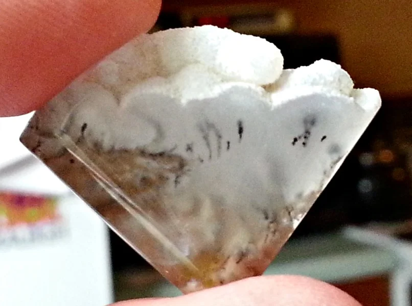 Plume agate shaped into a fan shaped cabochon, preserving the natural crystal formations.
