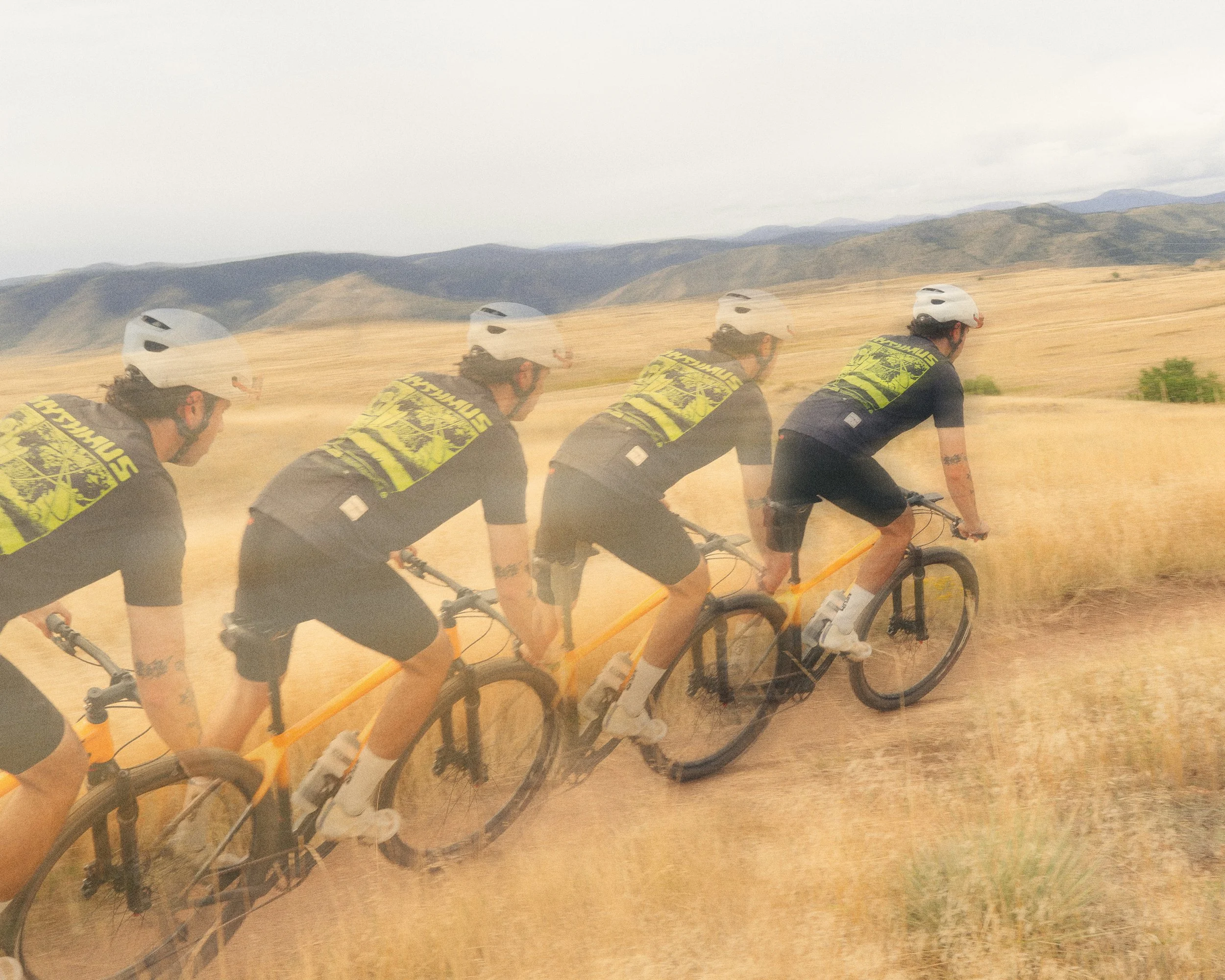 Man riding through mountain bike trails with motion blur,  wearing featured "Outride the Apocalypse" shirt from Rhythmus Equipment
