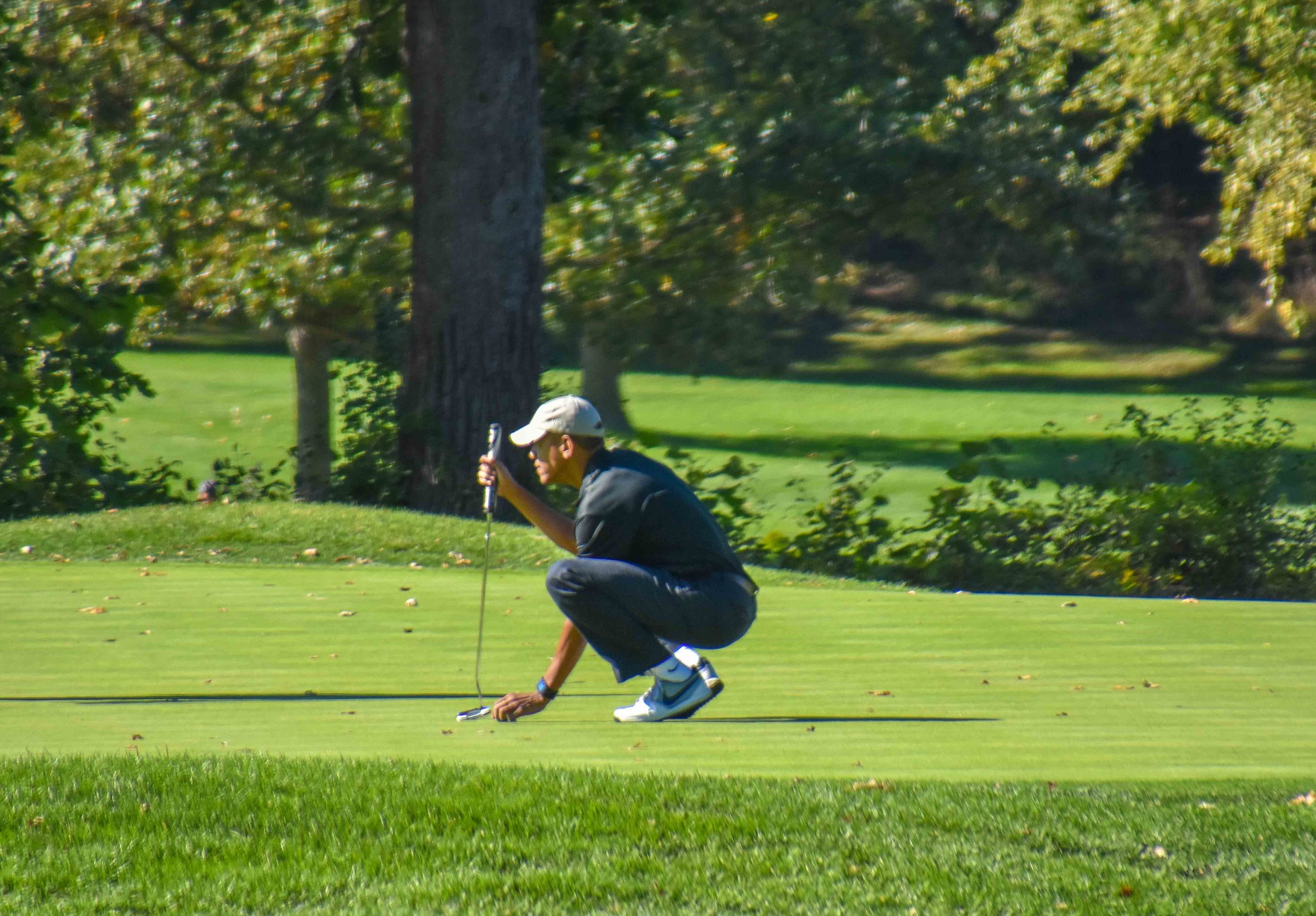 The President lines up a par putt on the hole adjacent to me.