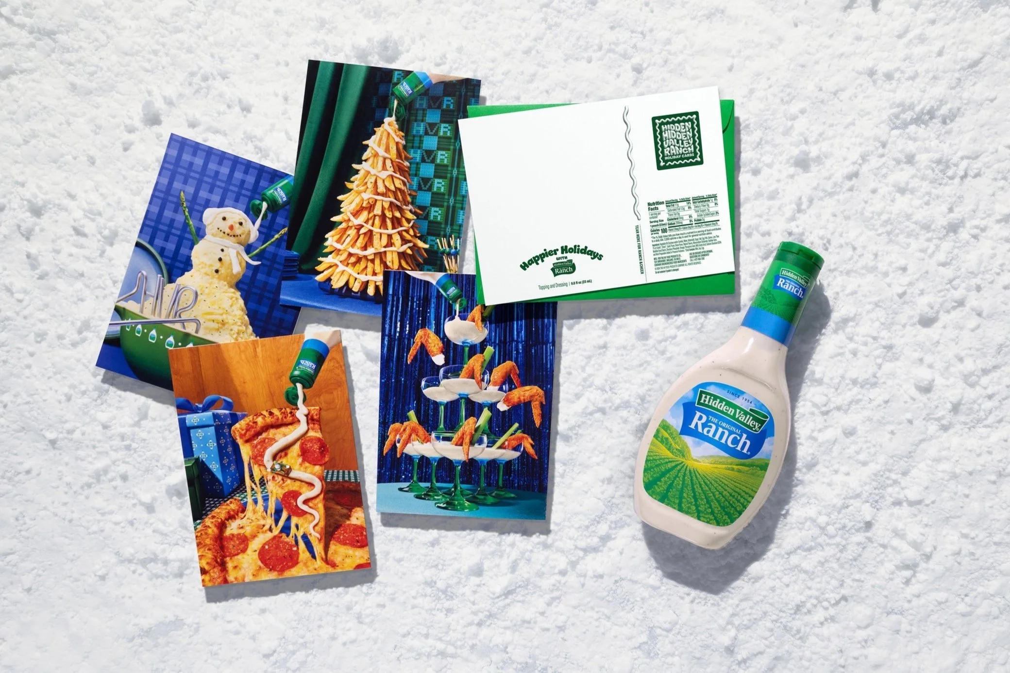 Collection of holiday-themed photographs, a bottle of Hidden Valley Ranch dressing, and a holiday card, all arranged on snow.