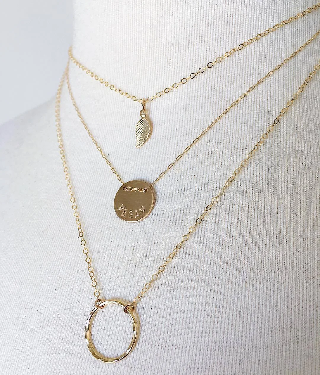 Compassion Layers in gold featuring the Earth Saver necklace with gold fill components + the 'VEGAN' Button Necklace in Gold + Gold Drop Circle Necklace by Jewels by SJB .