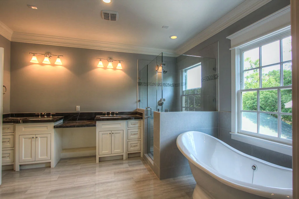 Master bathroom with freestanding tub, and hue shower with textured tile walls and stone flooring. Dark marble counters and smokey gray walls create a nice contrast of this suite from the remainder of the home.