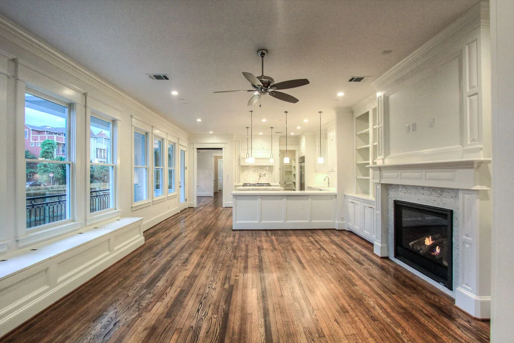 Spacious great room adjacent to kitchen has an wide open view of the greenbelt featuring the builder's signature site-built shelving and storage, including a built-in bench. Carrara tile surrounds the fireplace and reclaimed wood flooring throughout.