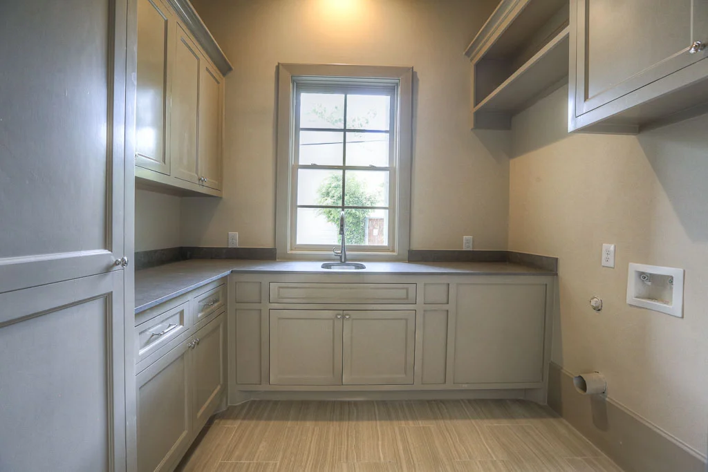 First floor utility room conveniently situated off the mud room. Whit extensive & thoughtful built-ins in both of these rooms. "Lagos Azul" limestone countertops in this room show the high level of attention to selections.