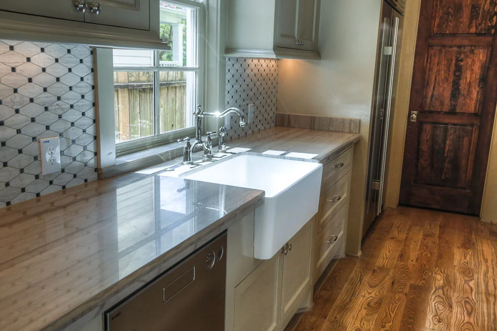 A deep apron sink is yet another one of the rustic features of the home, and under-cabinet lighting adds convenience. The door to the oversized pantry is the same dark stain as the ceiling beams.