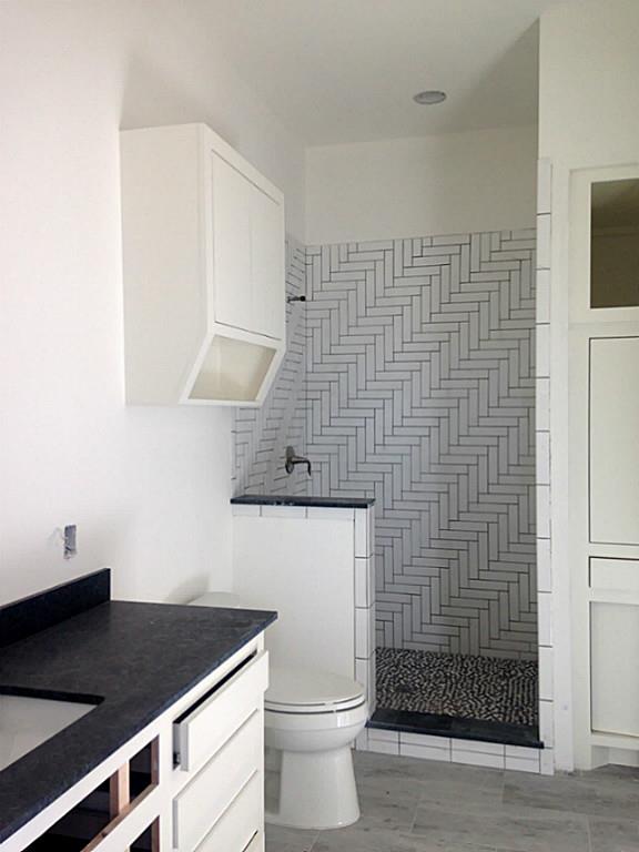 Secondary bathroom with leathered silver pearl countertop and original shower wall pattern gives this bathroom a crisp, classic look.