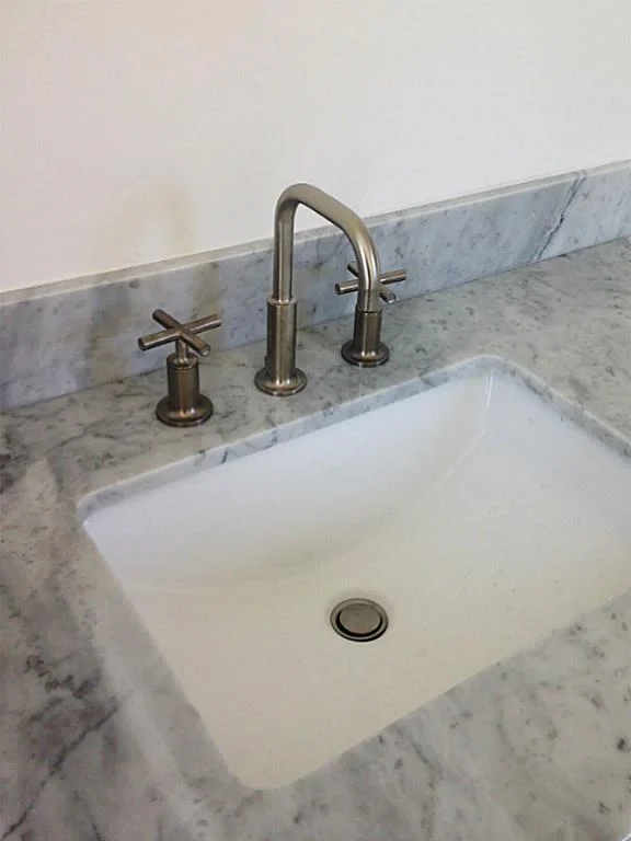 Detail of marble countertop, modern sink, and minimal brushed nickel faucet. Understated, this look has a timeless appeal.