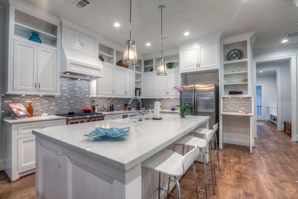 Kitchen features large island with seating, custom cabinetry, and a mosaic tile backsplash.