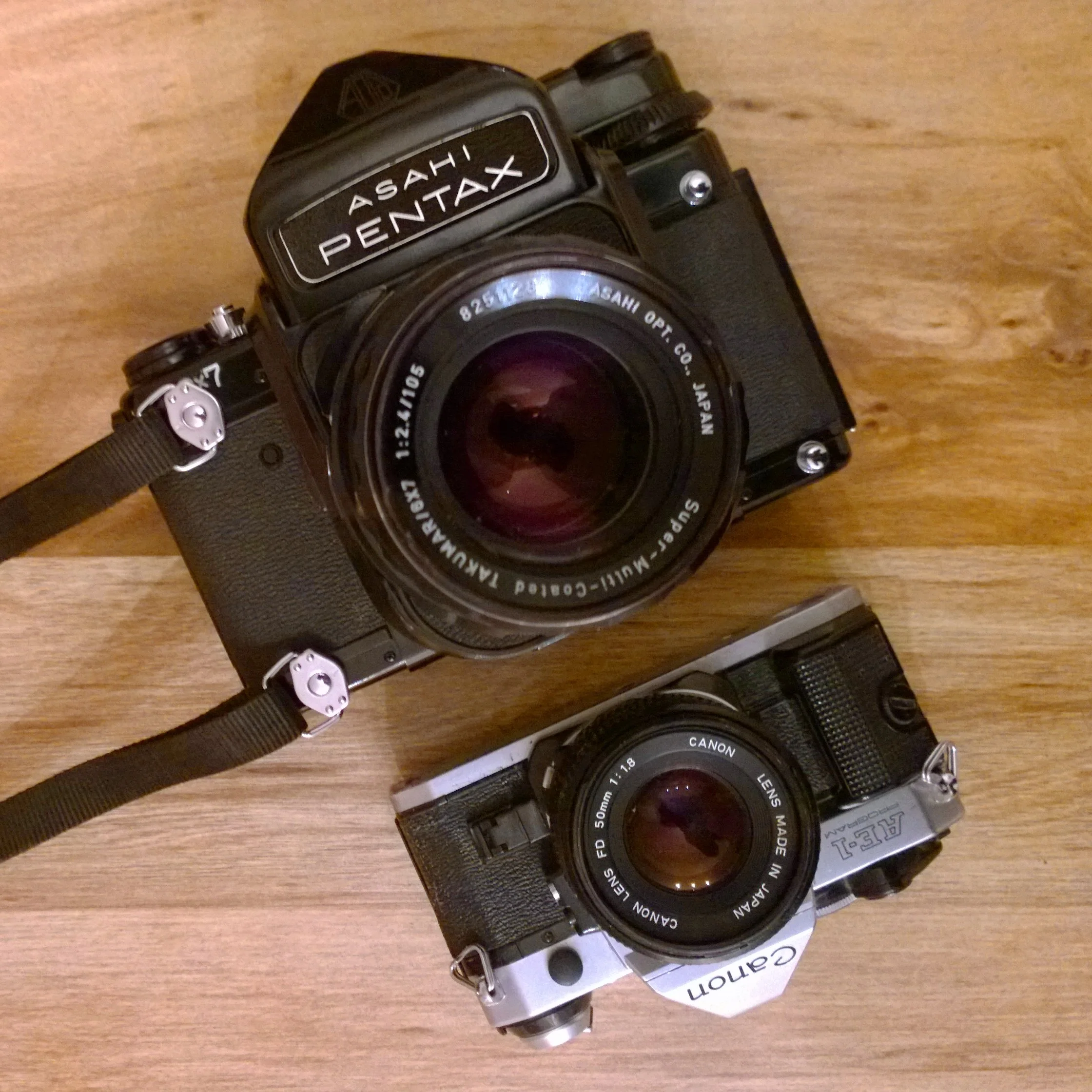 The Pentax 6x7 compared to a 35mm Canon AE-1, both shown with standard lenses.