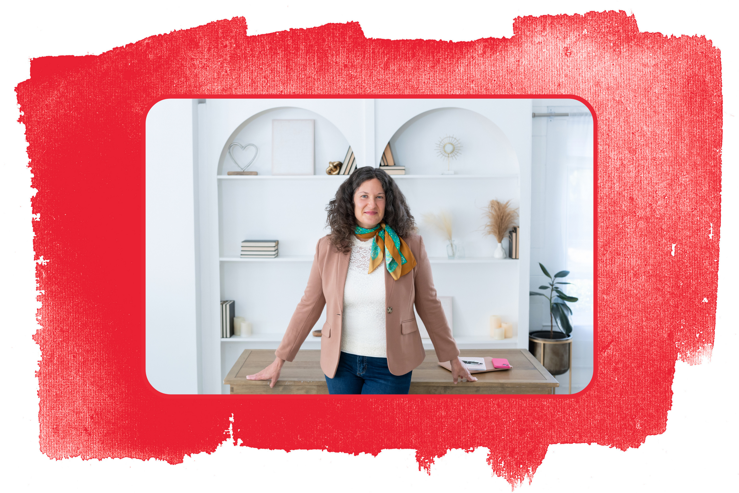 Sasha McDowell, a white woman with curly dark hair wearing a tan blazer and a colorful scarf, standing in a room with white shelves decorated with decorative objects. Photo is layered over a red paint swatch.