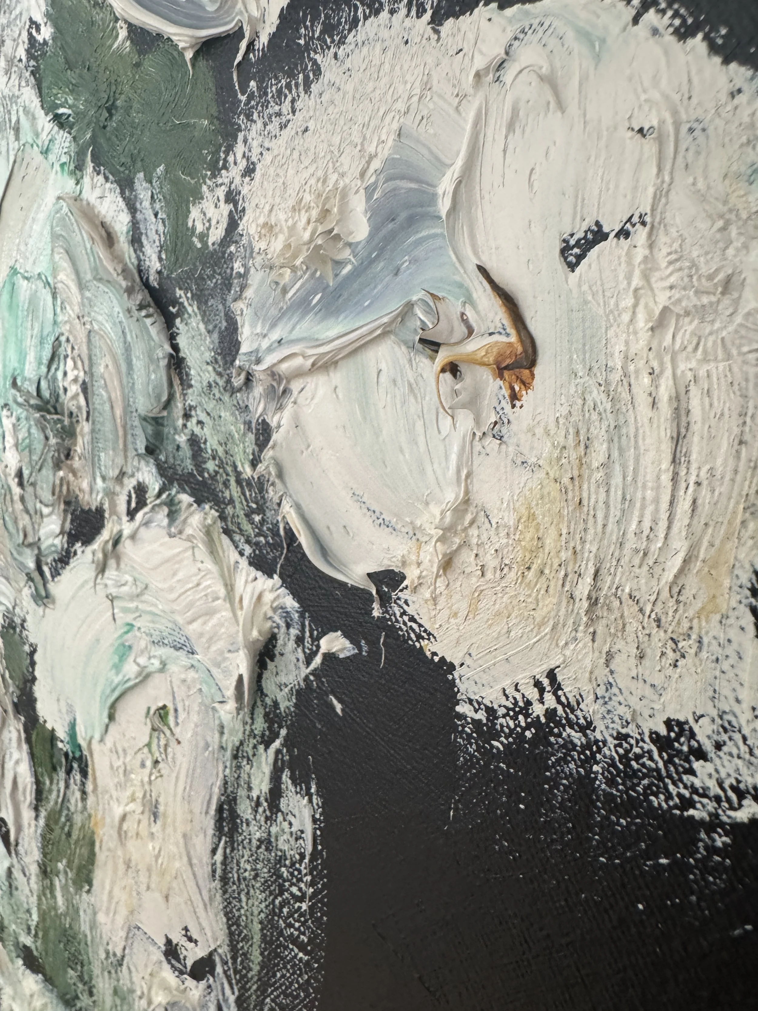 Close‑up of heavily textured paint in soft whites, creams, greens, and grays layered over a dark background in an abstract style.