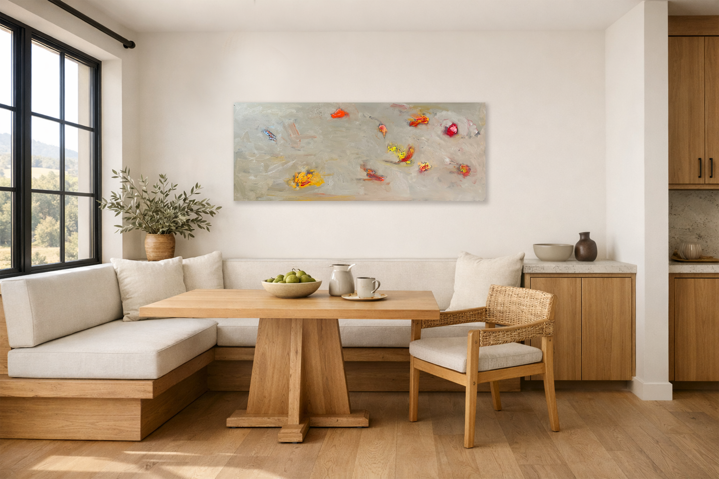 A large abstract painting with soft gray tones and bright accents hangs above a built‑in dining nook with a wood pedestal table, woven chair, and neutral cushions.