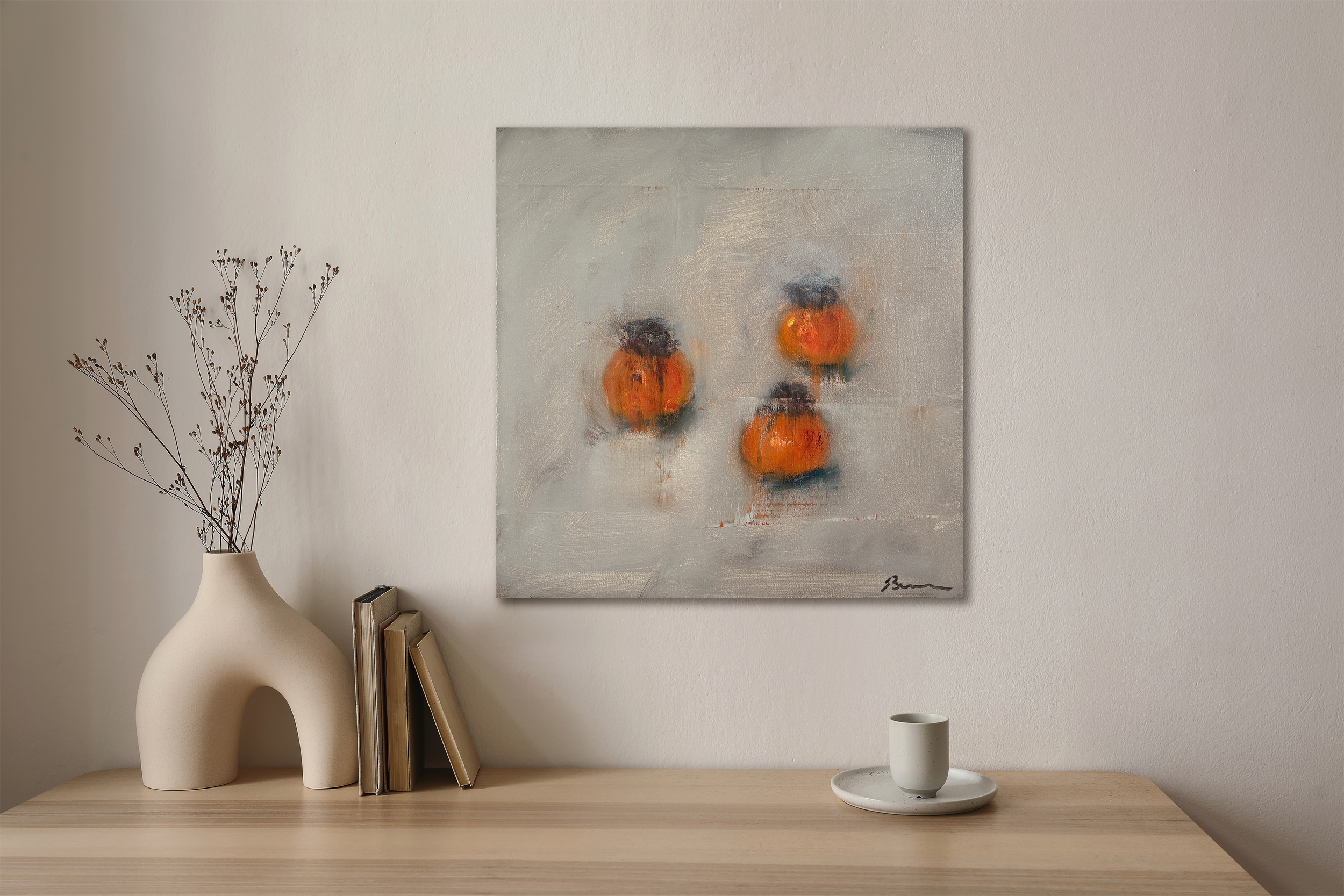 Minimalist interior with light wood table, ceramic vase, and abstract persimmons painting in soft orange and white tones, styled against a white wall.