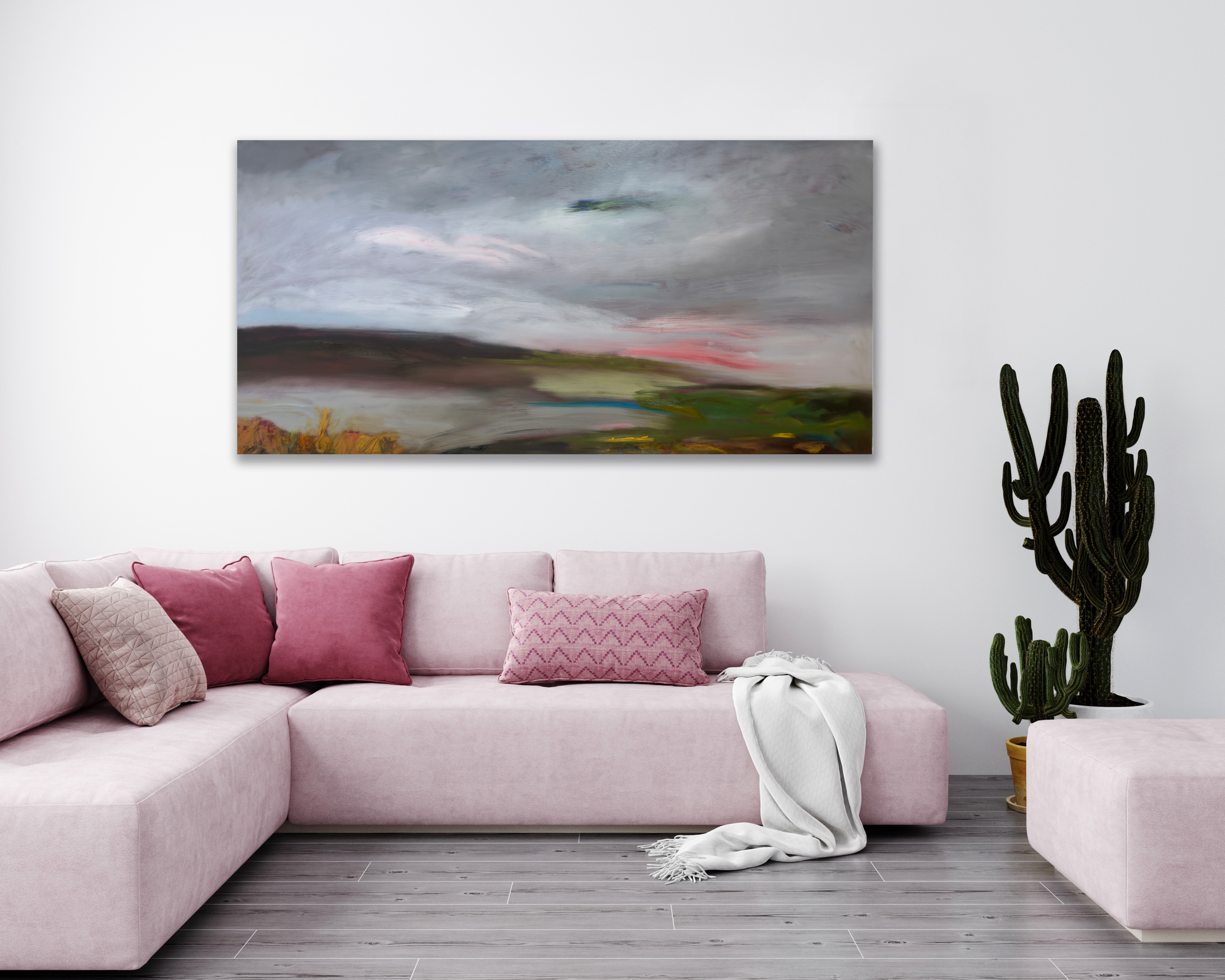 Abstract landscape painting with muted tones of gray, pink, and green hanging above a pink sofa in a modern living room.