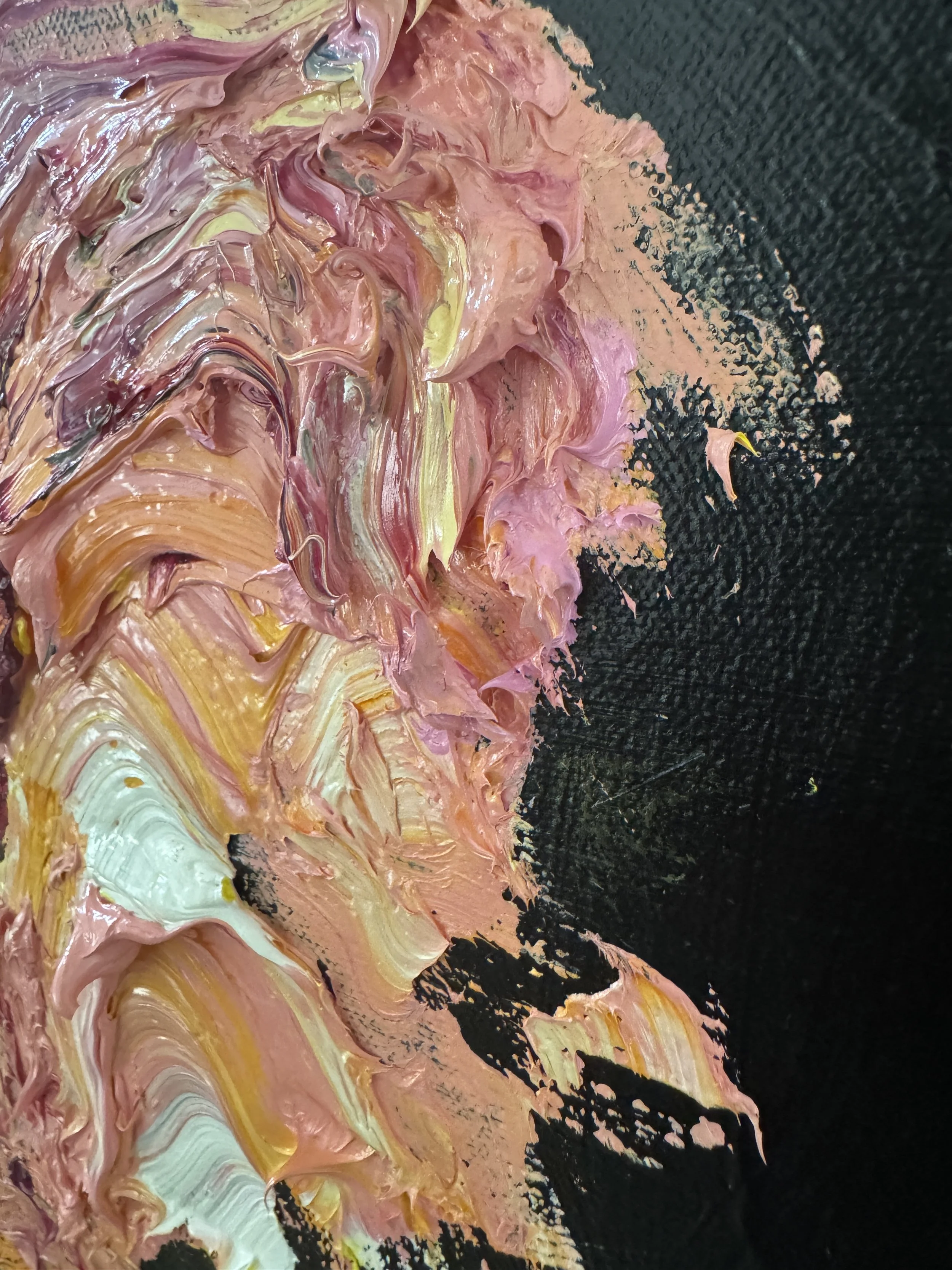 Close‑up of thick pink, peach, cream, and yellow paint strokes on a dark background.