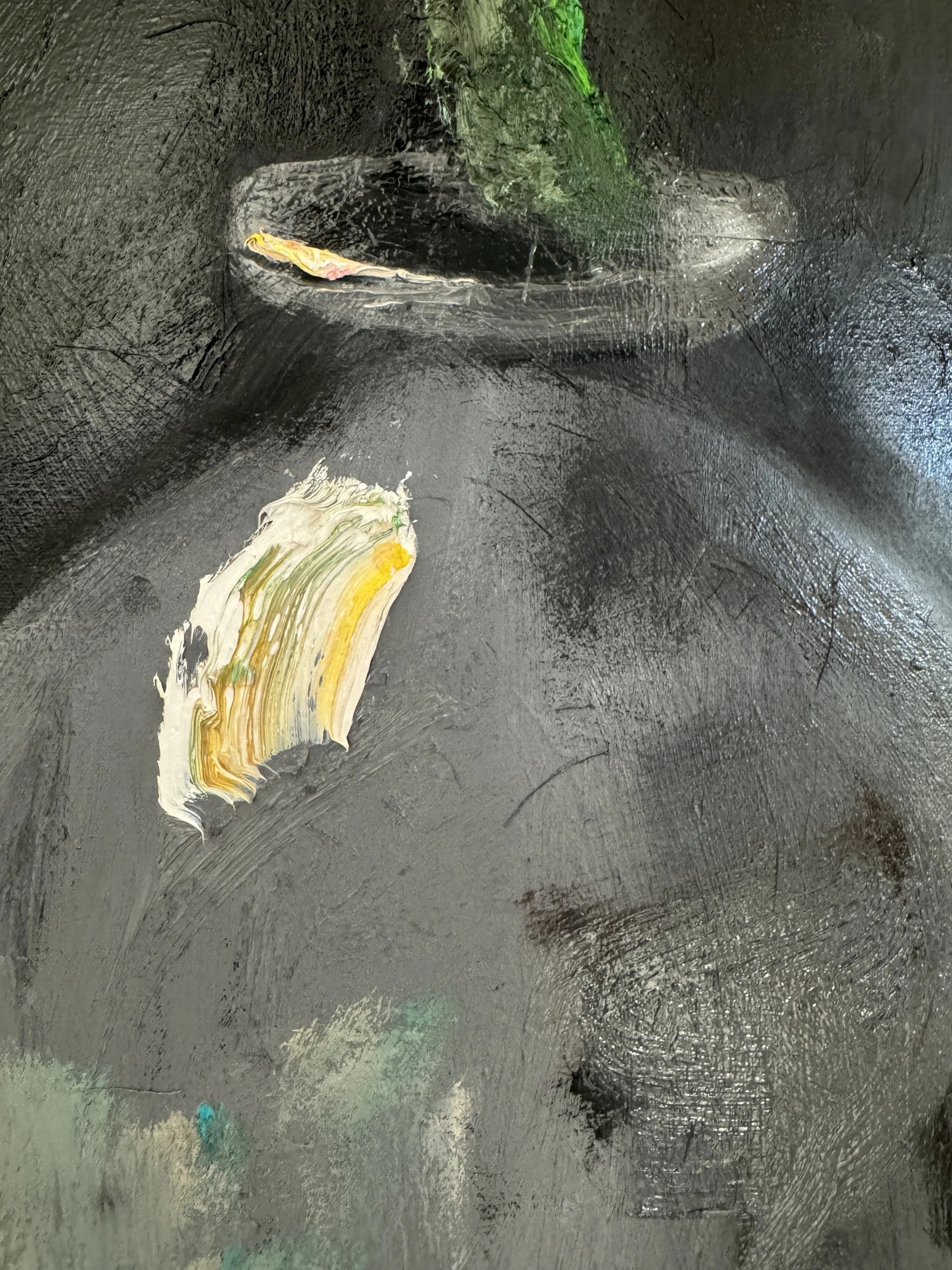 Close‑up of expressive brushstrokes in dark gray with patches of yellow, white, green, turquoise, and beige, highlighting layered paint texture.