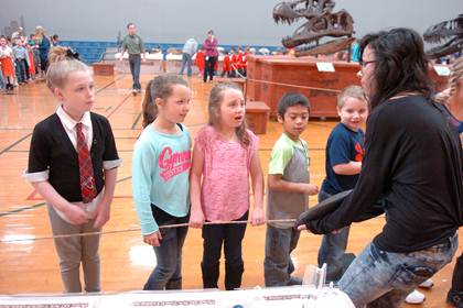 North Lamar High School art student Megan Grogan assists with the dinosaur exhibit by holding a large tooth so those touring can get a closer look. Inquiring as to what prehistoric animal the tooth belonged to are North Lamar elementary students Savannah Pickering, Berkley Smith, Grace Maddox, Luis Morales and Ryan Stanley.