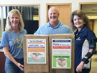 Public Information Officers, Carla Coleman of NLISD (left), and Jeanne Kraft of PISD (right), tape on posters to collection boxes for Bill Coleman of Liberty National Bank.