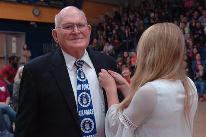 Air Force veteran Norman Davis receives a pin by a North Lamar Beta Club member as the band and choir perform Salute to the Armed Forces . 
