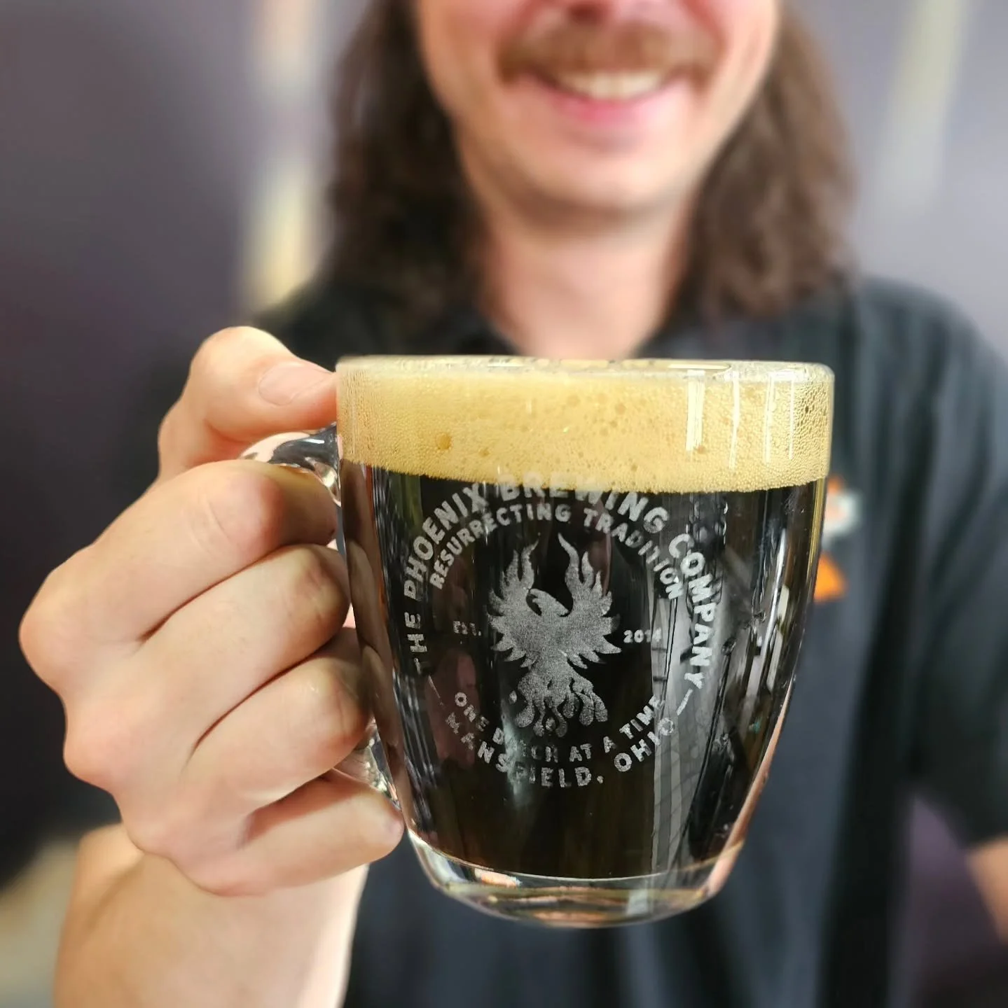 Branded glass mug with dark beer, from The Phoenix Brewing Company’s homepage gallery